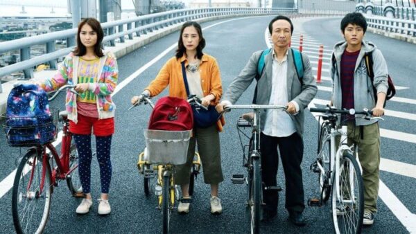 生存家族電影劇照,一家四口推著腳踏車走在高速公路上